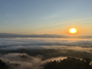 Obraz premium Sunrise over a misty valley with the sun glowing brightly