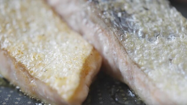 A close up of a piece of fish with a lot of seasoning on it. The seasoning is a mix of salt, pepper, and garlic powder. The fish is cooked