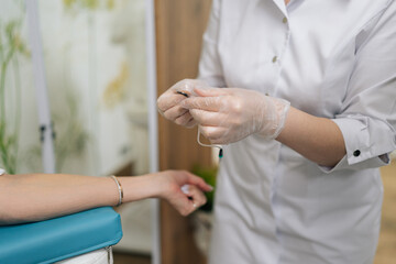 Cropped shot of unrecognizable woman patient receiving blood test preparation from medical professional, getting blood sample drawn for laboratory analysis in clinical healthcare environment.