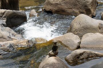 Small zen rock cairn stacked on a boulder in front of a splashing mountain river stream. © Irina
