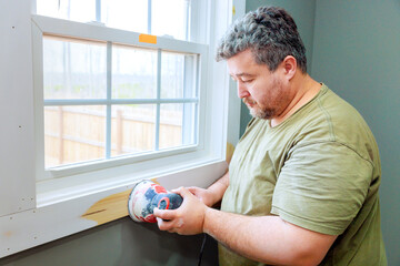 Contractor carefully applies putty to window frame, on his task during home renovation fresh paint...