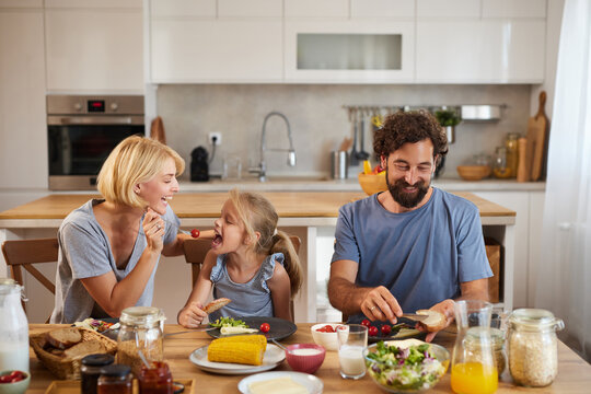 A family shares a delightful breakfast at their kitchen table, laughing and enjoying fresh fruits, bread, and orange juice while creating cherished moments.