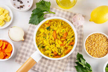 Tasty Italian Penicillin Soup, autumn winter immunity booster chicken vegetables orzo soup. Traditional european comfort food with ingredients for cooking on white table