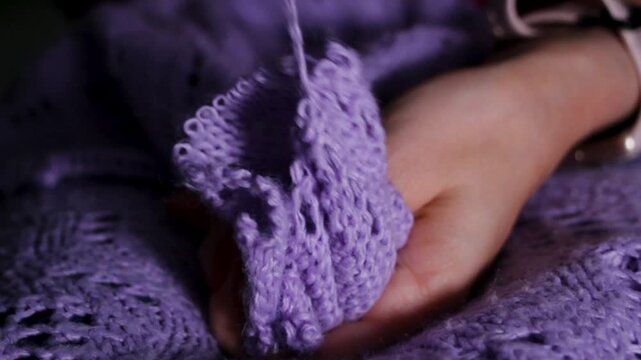 Yarn separates from knitwear, showing textile texture and recycled fiber. Female hands guide thread into ball. Concept of reuse as mindful stage in sustainable production.