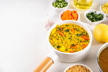 Tasty Italian Penicillin Soup, autumn winter immunity booster chicken vegetables orzo soup. Traditional european comfort food with ingredients for cooking on white table