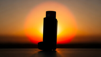 Inhaler asthma inhaler medical device for respiratory relief and treatment silhouette at sunset. 