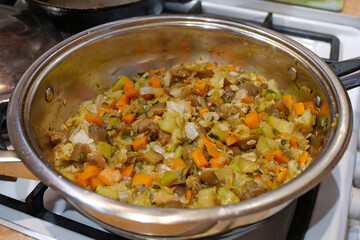 Vegetable stew is cooked on gas stove. Ragout in metal pan