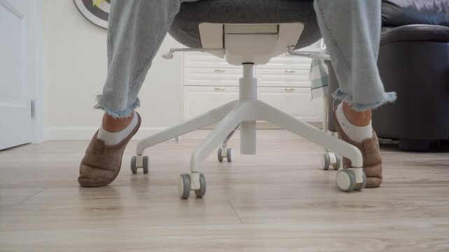 Woman Rolls Office Chair Backward, Creating Low Rattle on Wooden Floor.