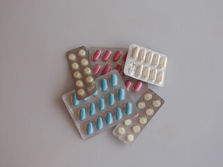 Various pills in blister packs on a plain white surface. A collection of different pills in blister packs are arranged on a clean, white background, ready for use