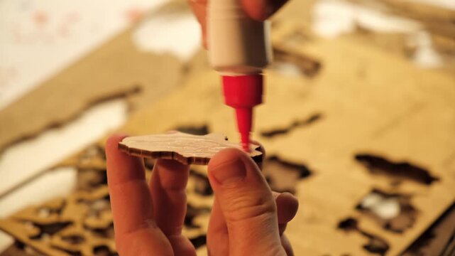 A man smears a wooden part with PVA glue in close-up. The creative process of creating DIY crafts. Gluing a world map from individual pieces of countries. Hobby concept. Carpentry. High quality 4K.