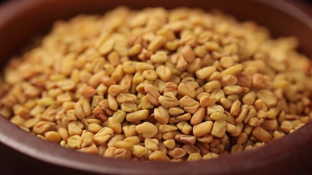 Fenugreek seeds in a brown wooden bowl rotating. Close-up shot