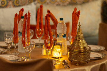Arabian theme dinner table set up, moroccan style lidded container in the foreground, Marrakech. Elegant table setting in a traditional Moroccan restaurant with warm lighting. 