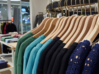 Knitted sweaters on hangers in shop for sale.