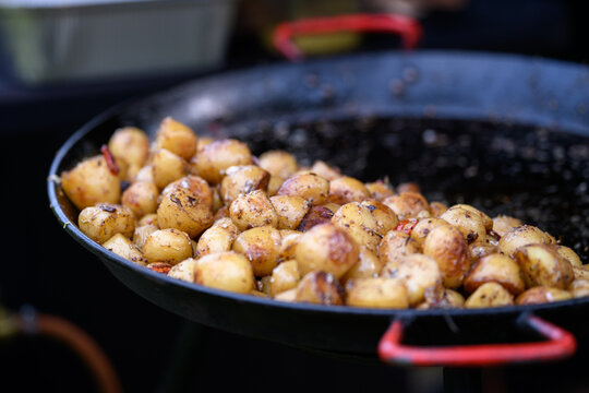 Close-up of freshly cooked fried potatoes in a large frying pan on a gas hob