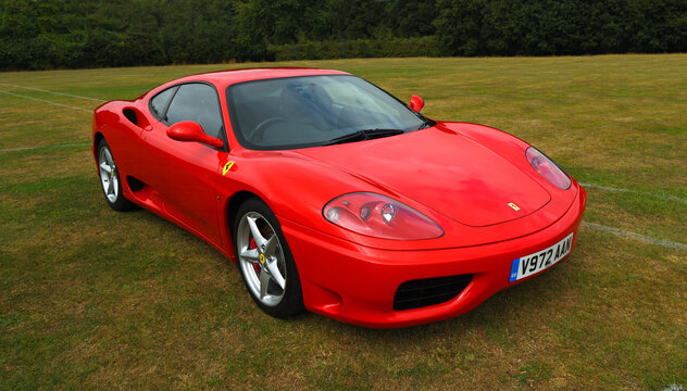 Classic  red Ferrari 360 Modena sports car parked on grass.