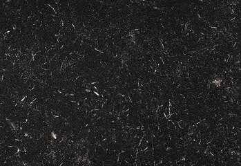 Close up macro shot of black granite texture with subtle white mineral flecks and polished finish, ideal for countertops, backsplashes, interiors and photography backdrops