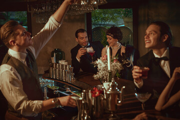 Retro-dressed people chatting at the bar and enjoying evening cocktails. Concept of bar promo, mixology marketing, nightlife visuals, luxury alcohol campaigns, and holiday content.