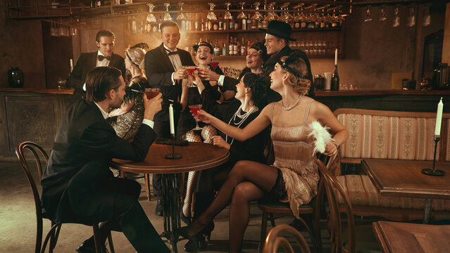 Retro celebration with smiling friends raising cocktails in warm vintage bar. Concept of Christmas nightlife visuals, bar marketing, fashion lifestyle, and premium retro event content. - Powered by Adobe