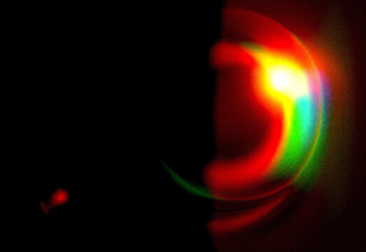 Abstract circular light flare with vibrant red, orange, yellow and green hues against dark background, creating a futuristic neon glow for use in tech, design, and multimedia