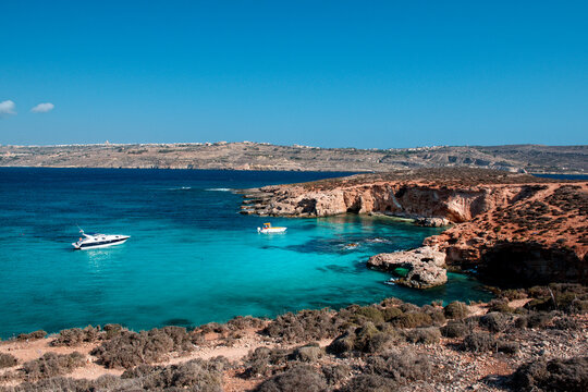 Two boats anchored in the turquoise waters of a coastal bay, Gozo, Malta
