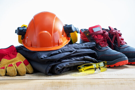 Safety helmet, safety shoes, safety suit, earmuffs, goggles cutresistant gloves on wooden table. Work safety protection equipment.