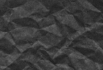 Close-up of a dark grayscale crumpled paper texture with prominent folds and subtle grain, creating a rich tonal background, suitable for design, typography, and art projects