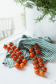 Fresh cherry tomatoes on the vine placed on a green kitchen cloth in soft natural window light.