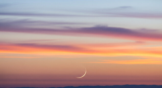 Thin Crescent Moon Hanging in Dramatic and Colorful Twilight Sky
A stunning, ultra-thin crescent moon is delicately suspended in a dramatic twilight sky, dominating the lower center of the frame - Powered by Adobe