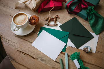 Overhead view of a cappuccino on a table with a blank card and wrapped Christmas gifts  and assorted festive decorations