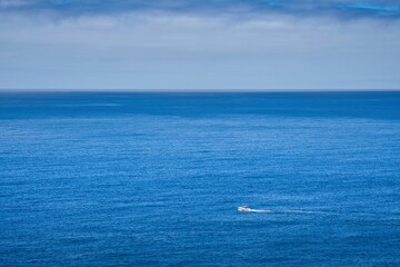 A boat is sailing in the ocean with a clear blue sky in the background