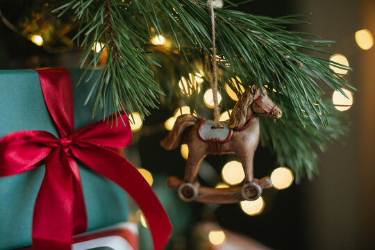 Full frame Close-up of a stack of wrapped Christmas gifts under an illuminated Christmas tree with a rocking horse decoration