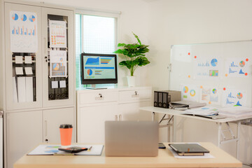 Businesswoman smiling while using laptop and talking on mobile phone at desk in office and at home or coffee shop.
