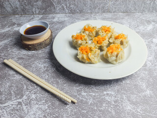 Shrimp and chicken dimsum served on a white plate with soy sauce on the side 