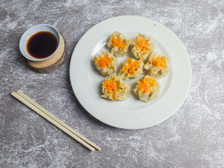 Shrimp and chicken dimsum served on a white plate with soy sauce on the side 