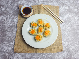 Shrimp and chicken dimsum served on a white plate with soy sauce on the side 