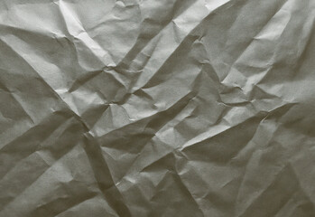 Close up of a crumpled textured gray paper surface with random folds and soft shadows, ideal for backgrounds in design projects, presentations, posters, layouts, and typography.