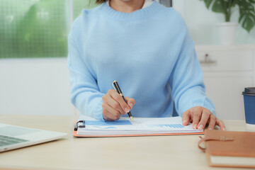 Businesswoman smiling while using laptop and talking on mobile phone at desk in office and at home or coffee shop.
