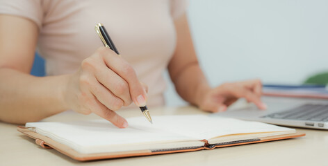 Businesswoman smiling while using laptop and talking on mobile phone at desk in office and at home or coffee shop.