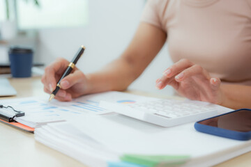 Businesswoman smiling while using laptop and talking on mobile phone at desk in office and at home or coffee shop.