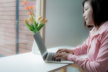 Businesswoman smiling while using laptop and talking on mobile phone at desk in office and at home or coffee shop.
