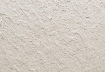Close up of a beige textured plaster wall with rough, uneven patterns and soft shadows, highlighting tactile wall texture for architectural design, interior decor, and background