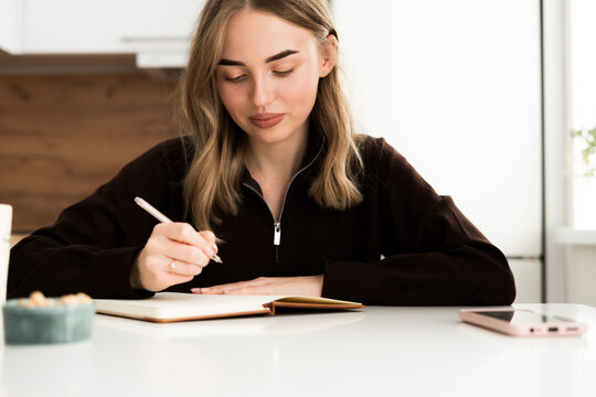Focused young woman writing notes in notebook thoughtful and concentrated. studying, journaling