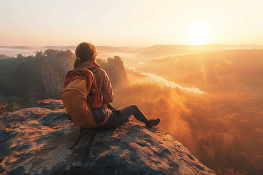 person sitting on cliff edge watching sunrise over calm valley, backpack beside them, warm golden tones and gentle mist, concept of reflection, self-discovery, and peaceful nature adventure - Powered by Adobe