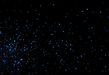 Close up of a dark background speckled with glowing blue particles forming a cosmic dust trail, an abstract technology concept with futuristic ambiance for dynamic visual projects