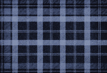 Close-up shot of dark blue plaid fabric texture with a woven check pattern, showing intersecting light and dark lines; a wool textile ideal for fashion, upholstery, and crafts.