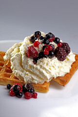 Isolated waffle with cream, syrup and toppings