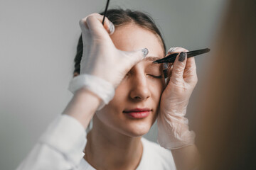 gentle application of brow shading by technician on caucasian client with focused precision © Strelciuc