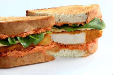 Close up of a chicken sandwich with toasted bread, lettuce and sauce