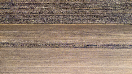 Aerial view of textured brown land with horizontal lines, representing agricultural fields or...