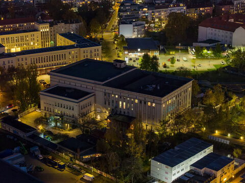 Aerial view of the iconic Berghain nightclub illuminated against the night sky, its stark facade a beacon amidst the urban sprawl, Berlin, Berlin, Germany.
